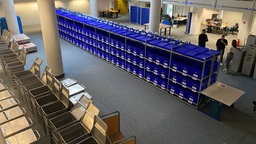 Mehrere Boxen und Container stehen für die Auszählung einer OB-Stichwahl in einem Raum.
