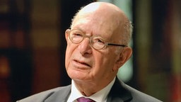 Portraitfoto von Bert Woudstra. Er trägt einen Anzug und eine runde Brille.