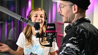 Zwei Menschen am Studio-Mikrofon von 1LIVE