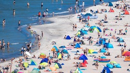 Menschen liegen am Strand und im Wasser