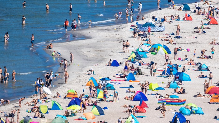 Menschen liegen am Strand und im Wasser