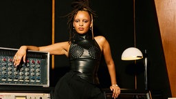 Camille Yembe steht vor einem Mischpult