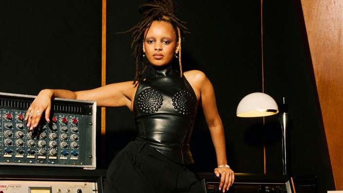 Camille Yembe steht vor einem Mischpult