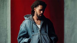  J. Cole – "Fall-Off" - der Künstler steht mit gesenktem Blick vor einer Betonwand. 