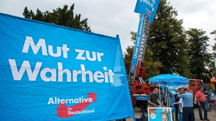 Passanten stehen am 01.09.2016 in Schwerin (Mecklenburg-Vorpommern) bei der Kundgebung zum Abschluss des AfD-Wahlkampfs in Mecklenburg-Vorpommern an einem Infostand der AfD