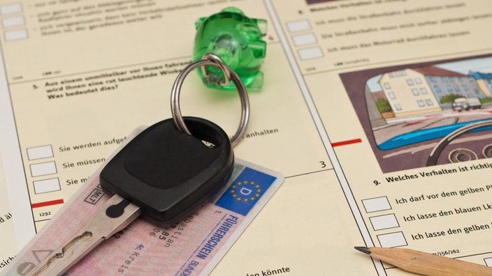 Ein Autoschlüssel und Fahrerlaubnis liegen auf Lernmaterialien zum theoretischen Teil der Führerscheinprüfung.