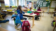 Schülerinnen und Schüler einer Grundschule, sitzen mit Abstand in ihrem Klassenraum