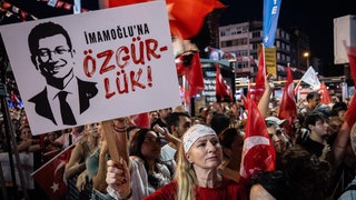 Eine Frau hält ein Plakat mit der Aufschrift „Freiheit für Ekrem Imamoglu“. 
