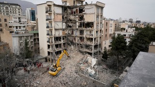 Rettungskräfte des iranischen Roten Halbmonds räumen mit einem Bulldozer die Trümmer eines Wohnhauses weg, das bei einem früheren amerikanisch-israelischen Angriff getroffen wurde. 