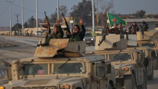 Ein Konvoi kurdischer Kämpfer der Syrischen Demokratischen Kräfte (SDF) zeigt Siegeszeichen, als er sich kurz vor dem Ende eines viertägigen Waffenstillstands.
