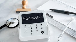 Fotomontage, Symbolfoto zur Pflegestufe 1 mit Gerätedisplay, Gesundheitskarte, Stethoskop und Stempel als Hinweis auf Pflegeversicherung und Reformen