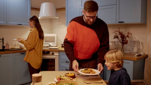 Eine Familie, Vater, Mutter und Kind, in der Küche