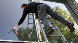 Un pulitore sta lavando una vetrata arrampicato su una scala
