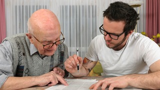 Ein älterer und ein jüngerer Mann füllen die Steuererklärung aus