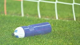 Eine blaue Trinkflasche liegt in einem Fußballtor