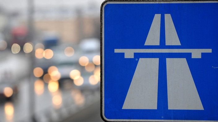 Ein Autobahnschild vor einer belebten Autobahnstrecke