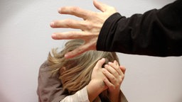 Ein Kind versucht, sich vor einer schlagenden Hand zu schützen