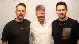 Revolverheld zu Gast bei WDR 2: Bandmitglieder Kristoffer Hünecker (l) und Johannes Strate (r) mit Moderator Johannes Simon 