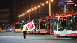 Ein Mitarbeiter geht im Busdepot der Stadtwerke Bonn an abgestellten Bussen entlang. 