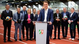 Hendrik Wüst (CDU), Ministerpräsident von Nordrhein-Westfalen spricht am 2.12.25 bei einer Pressekonferenz über Neuerungen des Bewerbungskonzepts für die olympischen und paralympischen Spiele. Hinter ihm stehen die Vertreter der Host-Städte. 