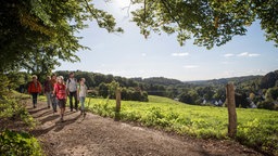 Mehrere Personen unterschiedlichen Alters sind auf einem Wanderweg unterwegs.