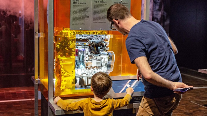 Ein Mann und ein Kind stehen an einer Station der DASA-Ausstellung "Feuer".