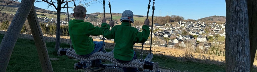 Zwei Kinder sitzen auf einer Schaukel