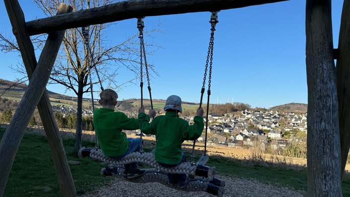 Zwei Kinder sitzen auf einer Schaukel