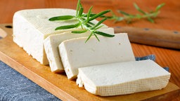 Tofu, aufgeschnitten auf einem Holzbrett