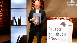 Der Autor und Journalist Konstantin Richter hält am 8. Juni 2026 sein Buch Dreihundert Männer Aufstieg und Fall der Deutschland AG in den Händen. Dafür ist er mit dem Deutschen Sachbuchpreis 2026 ausgezeichnet worden.