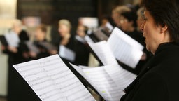 Chormitglieder singen mit Noten in der Hand.