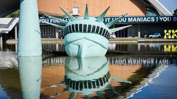 Der halbe Kopf einer aufblasbaren Freiheitsstatue, das Kunstwerk „Status of Liberty“ liegt in dem Gewässer vor dem Haus der Kulturen der Welt.