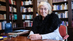 Die Journalistin und Moderatorin Carmen Thomas sitzt in einer Bibliothek.