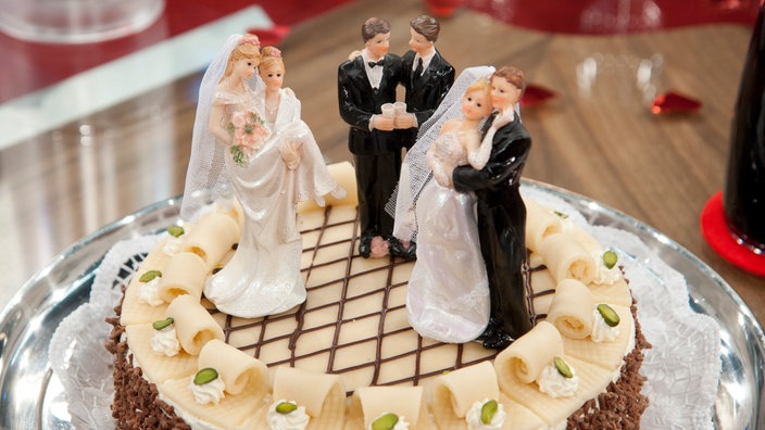 Eine Hochzeitstorte mit Dekoration dreier Hochzeitspaare: Ein lesbisches, ein heterosexuelles und ein schwules Brautpaar.