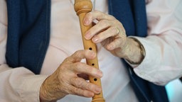 Seniorin spielt Flöte: Nahaufnahme der Hände und des Instruments.