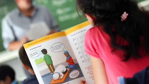 Ein Mädchen liest in einer Schule während des islamischen Religionsunterrichts in einem Schulbuch.
