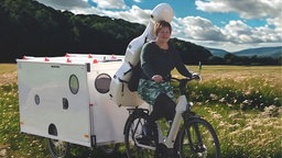 Katja Zakotnik auf ihrem Fahrrad mit Anhänger und Cello