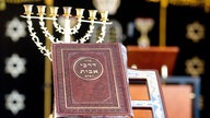 Ein jüdisches Gebetsbuch steht in der neuen Synagoge des Jüdisch-Bucharisch-Sefardischen Zentrums in Hannover vor einer Menora