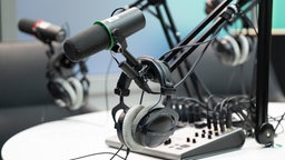 Mikrofon und Kopfhörer hängen in einem Podcast-Studio