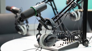 Mikrofon und Kopfhörer hängen in einem Podcast-Studio
