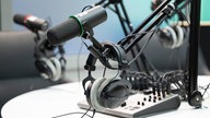 Mikrofon und Kopfhörer hängen in einem Podcast-Studio