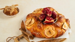 Süßspeisen zu Rosch ha-Schana auf einem Tisch: Challah, Honig, Granatäpfel und Äpfel