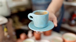 Hände halten eine Kaffeetasse.