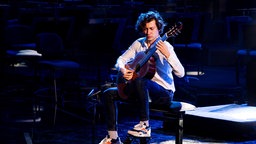 Thibaut Garcia spielt Gitarre auf einer Bühne.