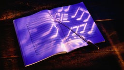 Partitur mit Taktstock in lila Licht