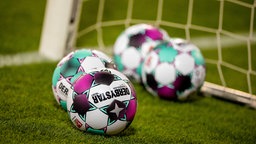 Symbolfoto: Verschiedene Fußbälle, hier bei einer Zweitliga-Partie 2020, liegen neben dem Tor auf dem Rasen.