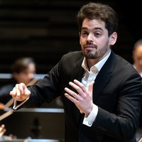 Lahav Shani dirigiert Musiker und Musikerinnen eines Orchesters.