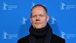 Porträtaufnahme des Komponisten Max Richter vor einer blauen Wand mit dem Logo der Berlinale.