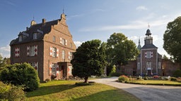 Gebäude von Schloss Hertefeld im tiefstehenden Sonnenlicht.