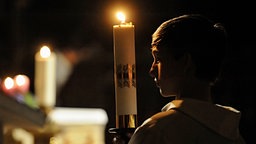 Das Beitragsbild der WDR3 "Vesper Rorate caeli &  die Viola d’amore" zeigt einen Messdiener der eine Kerze trägt in einer Rorate Caeli Messe.